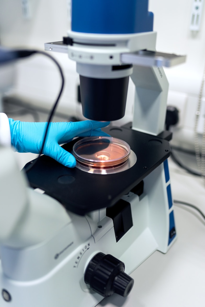 Gloved hand placing a sample under a microscope